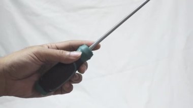 Yıldız tornavidayı tutan bir elin yakın çekimi. Beyaz arkaplanda tornavida tutuluyor.