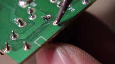 Hassas bir elektronik montaj işlemi sırasında elektronik bileşenleri devre kartına lehimlemek.