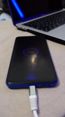 Bilgisayarın yanındaki masada bir akıllı telefon şarj ediliyor, ileri turbo şarj teknolojisi kullanılarak hızlı şarj edilen bir animasyon gösteriliyor