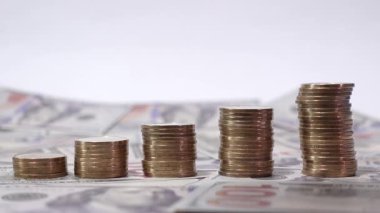 Yükselen dört madeni para yığını bir el ile üste bir madeni para koyar, bir arkaplan üzerine kurulur, zenginlik ve başarı çağrıştırır..