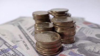 Kağıt para biriminin üzerine düzgünce istiflenmiş sikkelerin yakın çekimi sembolize eder. Resim, profesyonel ve pratik odaklı tasarruf, parasal işlemler ve yatırım fikirlerini iletiyor.