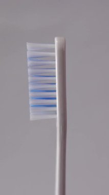 Mavi tüylü bir diş fırçasının yakından görüntüsü, minimalist ve modern bir estetik, ağız bakımı ve temiz tasarım sadeliğini vurguluyor..