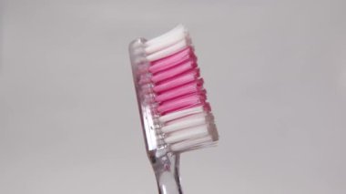 Yumuşak bir arka planı olan pembe ve beyaz bir diş fırçasının detaylı görüntüsü. Arkaplanda diş fırçası izole