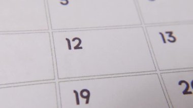 The 12th on the calendar is circled in red marker in a close-up macro shot on a white page, symbolizing an important day or reminder.