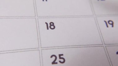 Takvimdeki 18 'i kırmızı işaretle işaretlenmiş beyaz bir sayfadaki makro çekimde önemli bir günü ya da hatırlatıcıyı simgeliyor..