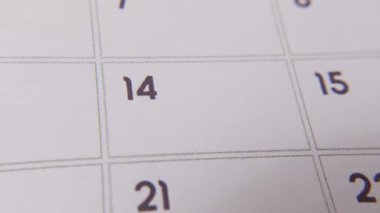 Takvimin 14 'üncüsü kırmızı işaretle işaretlenmiş beyaz bir sayfada yakın plan bir makro karede, önemli bir günü ya da hatırlatıcıyı simgeliyor..