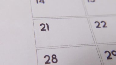 Takvimdeki 21. bölüm kırmızı işaretle işaretlenmiştir. Beyaz bir sayfadaki yakın çekim, önemli bir günü ya da hatırlatıcıyı simgeler..