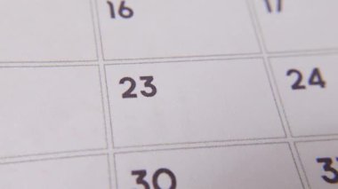 Takvimdeki 23 'ü kırmızı işaretle işaretlenmiş. Beyaz bir sayfada yakın çekim yapılmış. Önemli bir günü ya da hatırlatmayı simgeliyor..
