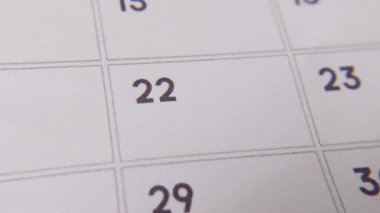 Takvimdeki 22. 'si kırmızı işaretle işaretlenmiş beyaz bir sayfadaki makro çekimde önemli bir günü ya da hatırlatıcıyı simgeliyor..