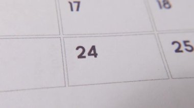 Takvimdeki 24 'ü kırmızı kalemle işaretlenmiş. Beyaz bir sayfada yakın çekim yapılmış. Önemli bir günü ya da hatırlatıcıyı simgeliyor..