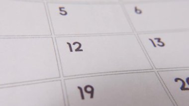 12 numaralı tarih işaretleniyor, takvimde kırmızı haçla vurgulanan sayıya odaklanıyor. Teslim tarihlerini, hatırlatıcıları, planlamaları ve zaman yönetimini temsil eder