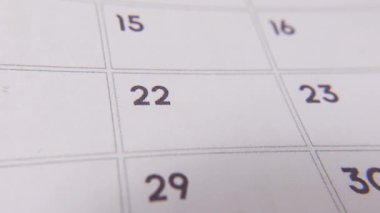 22 numaralı tarih işaretleniyor, takvimde kırmızı haçla vurgulanan sayıya odaklanıyor. Teslim tarihlerini, hatırlatıcıları, planlamaları ve zaman yönetimini temsil eder