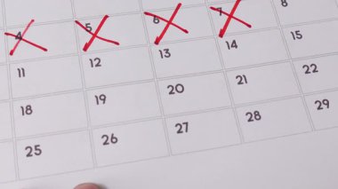 Takvimde günlerin üstünü kırmızı işaretle çizen bir el geri sayımı, planlamayı ya da zaman geçirmeyi simgeliyor..