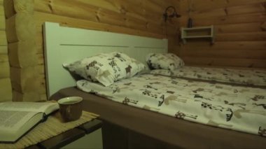 Kütük bir binada, bir bardak sıcak çayla bir yatak odasının resmi ve açık bir kitap.