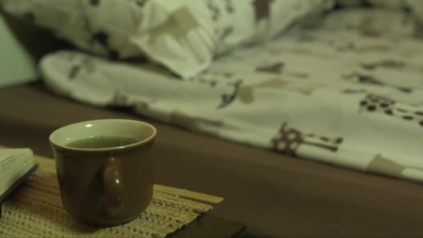 ベッドルームでティーカップとオープンブックのドリーショット — ストック動画