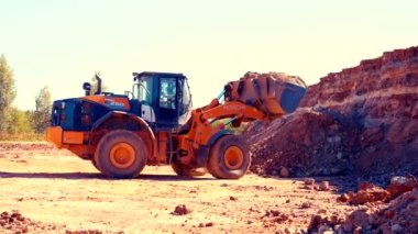 Büyük yükleyici kovasını kırmızı kille doldurur. 4k.