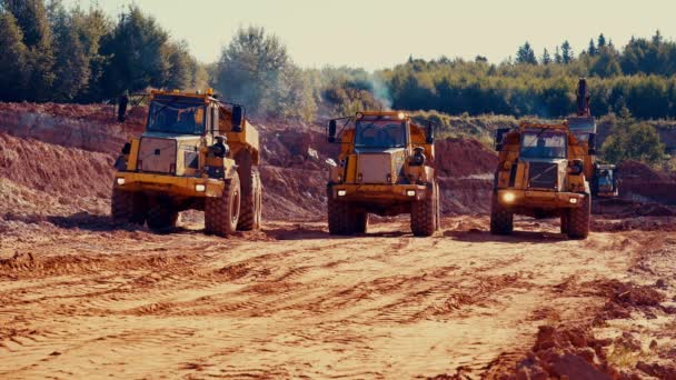 粘土採石場を離れる3つのダンプトラックの静的なショット 音がする バックグラウンドで掘削機 — ストック動画