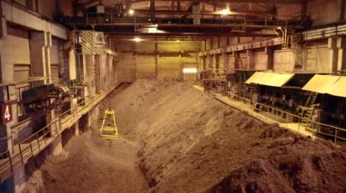 Sarı vinç, depoda kil taşıyan kovayı tutuyor. 4k.