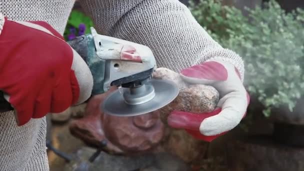 アーティストはグラインダーで石をカットします 手に持っている石を磨いた作家の手持ちカメラ — ストック動画
