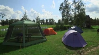 Kamp alanında çeşitli çadırlar. Çimenlikteki birkaç çadırın buharlı görüntüleri. Yemek masası çadırda..
