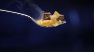 Buharda pişen pilavın statik makro çekimi ve çataldan atılan et parçaları.