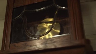 Camın arkasında ileri geri sallanan eski saat kolyesinin statik görüntüsü.