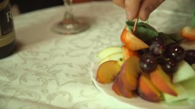 Çilekleri meyve tabağından, bir şişe şampanyadan, tatlıdan alan parmakları yakından çek.