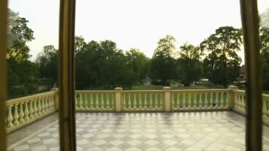 ... sarayın balkonuna doğru giderken, ortasında yuvarlak bir çiçek tarhı olan güzel yeşil avlu manzaralı bir fotoğraf çekilmiştir.