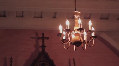 Kilisenin tavanında çok basit bir metal avizenin arka planda bir haçla yakın plan fotoğrafı.