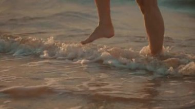 Denizin güzel köpüren dalgaları üzerinde yürüyen bir kadının yakın çekim görüntüsü, 4k, yavaş çekim.