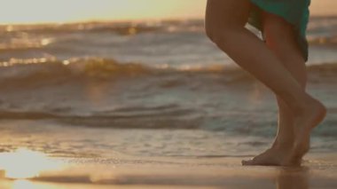 Denizin güzel köpüren dalgaları üzerinde yürüyen bir kadının yakın çekim görüntüsü, 4k, yavaş çekim.