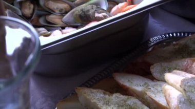Yakın çekim kızarmış beyaz ekmek, istiridye, karides, aşçı kepçeyle çorbayı dolduruyor.