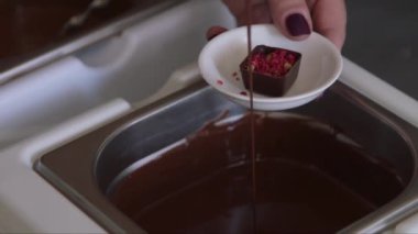 Bir kadının yeni doldurulmuş şekere sıvı çikolata dökerkenki yakın plan resmi.