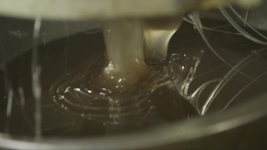 Bir kabın içine dökülen esnek bir karamel kütlesinin yakın çekim görüntüsü.