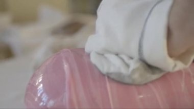 Pasta şefinin çok büyük bir parça pembe karamel hamurunu yoğururken yakın plan çekimleri.