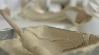 Karamel hamurunun kütlesini esneyen, fırlatan ve yoğuran iki şekerlemecinin el ele tutuşunu yakından çek.