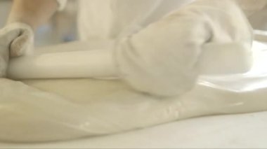 Bir hamur işi şefinin büyük bir beyaz karamel yığınını yuvarlarken yakın plan çekimleri.