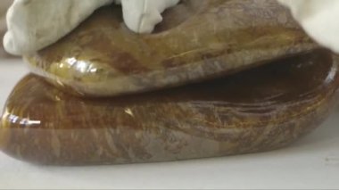 Hamur işi şefinin büyük, kahverengi, parlak bir karamel hamurunu yoğururken yakın plan çekimleri.