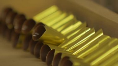 Pasta şefinin statik yavaş çekim makro çekimi. İçi çikolatalı, altın koni şeklinde bitmemiş şeker ekliyor.