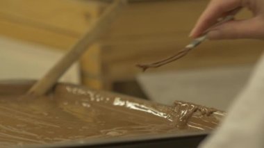 Marzipan topunu sıvı çikolatayla kaplayan şekerlemecinin yakın çekim statik yavaş çekimi.