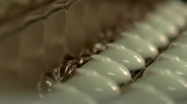 durağan yavaş çekim yakın çekim beyaz marşmelovların konveyör hattında sıvı çikolatayla kaplanması