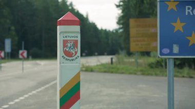 Litvanya Cumhuriyeti sınır işaretinin statik yakın çekim görüntüleri, arka planda otobüs geçiyor