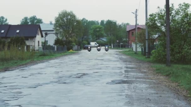 雨の日に村を運転する3人のチョッパーの広いショット — ストック動画