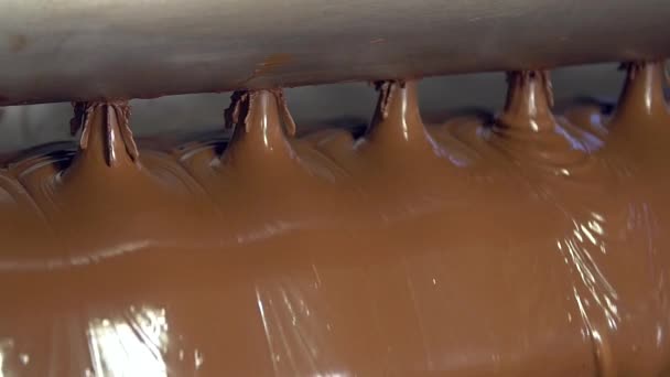 ステンレス鋼の管からいくつかの開口部を通って流れる液体のチョコレートの静的な遅い動き媒体ショット — ストック動画