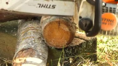 Bir adamın elektrikli testereyle kütük keserken yakın plan çekimleri.