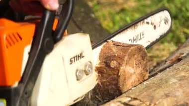 Bir adamın elektrikli testereyle kütük keserken yakın plan çekimleri.