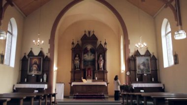 Orta büyüklükteki bir kilisede Üç Sunak 'ın Statik Geniş Çekimi, Ayakta Duran ve Dua Eden Kadın