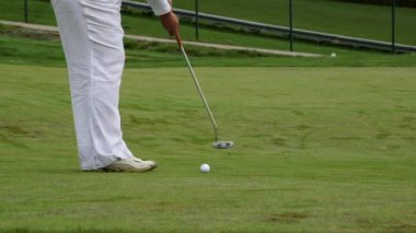 Kadın topa bir sopayla vurur ve deliği ıskalar, sonra vurur. Golf, oyuncuların topu deliğe sokmak için kulüpleri kullandıkları bir klüp ve top sporudur..