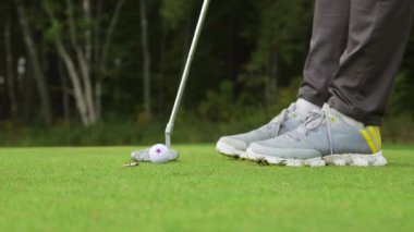 Golfçü sopayla vuruş yapıyor. Golf, oyuncuların topu deliğe sokmak için kulüpleri kullandıkları bir klüp ve top sporudur..