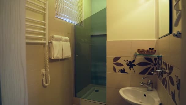 非常にシンプルなゲストハウスシャワー室のインテリア ガラスのドア シンク タオル ドライヤー タオルが付いているシャワー シャワーのドアのための興味深い傾斜の設計 — ストック動画